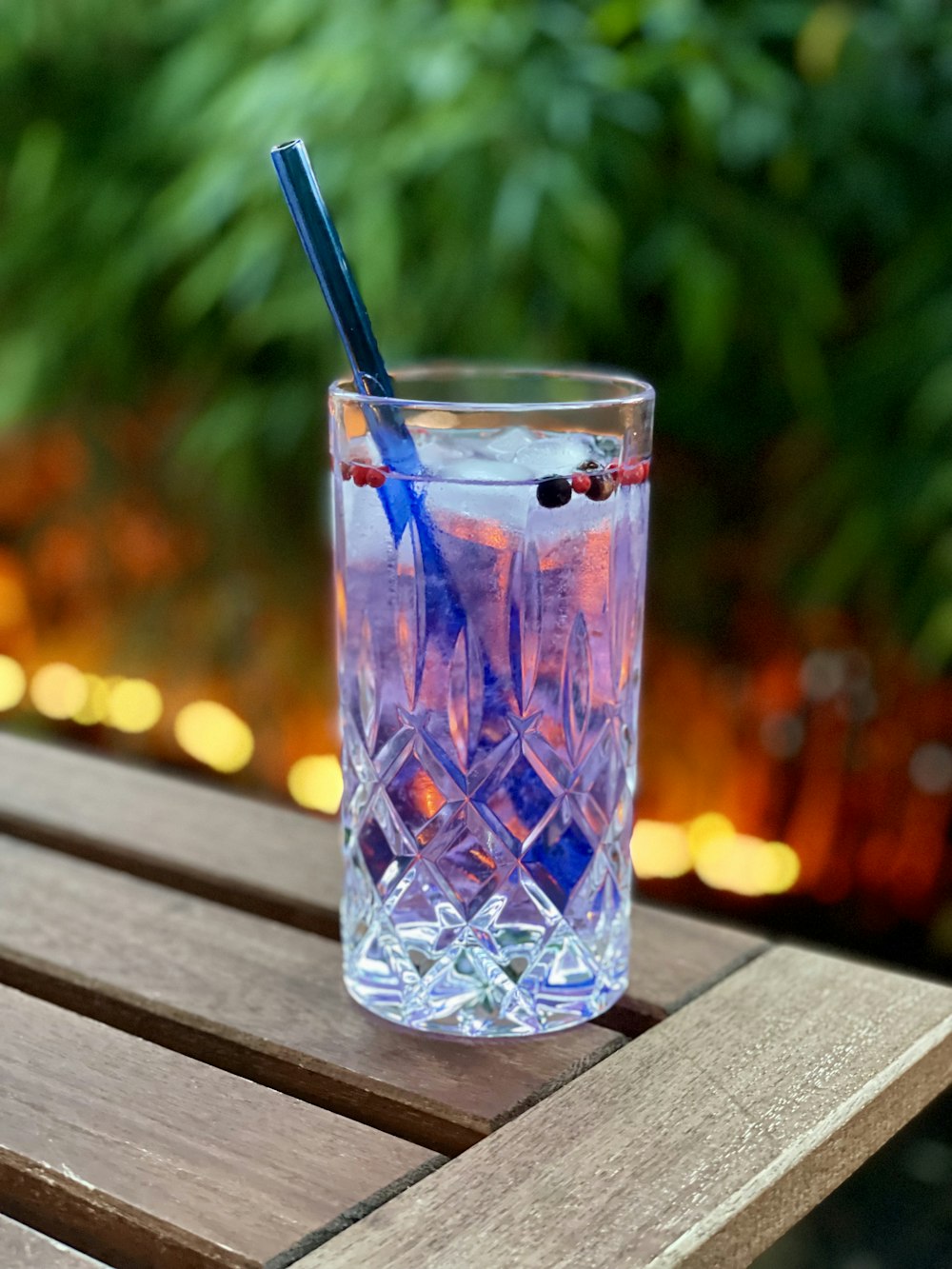 blue and clear drinking glass with black straw on brown wooden table