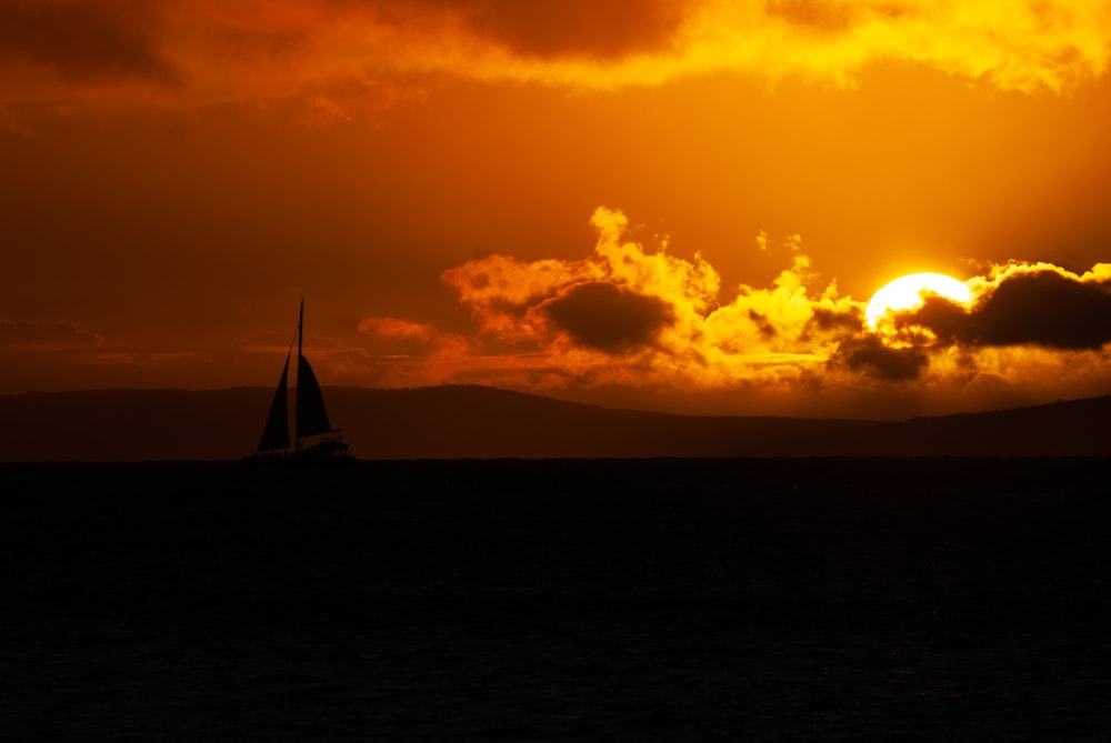 silhouette of sailboat on sea during sunset