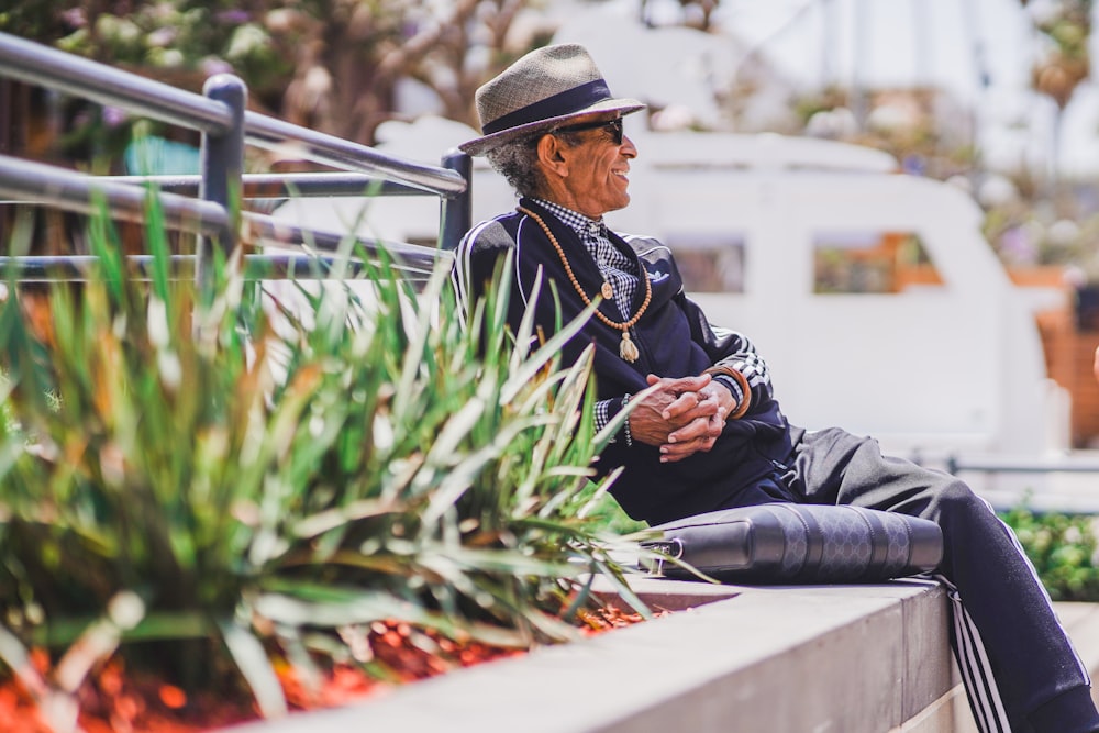 man in black jacket and black pants sitting on gray concrete bench during daytime