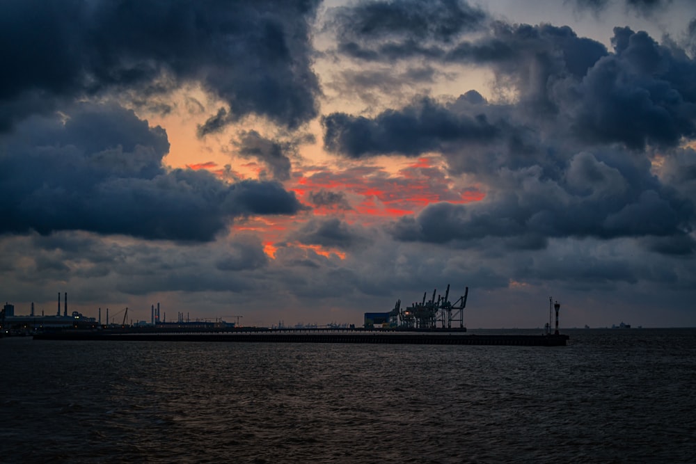 silhouette of ship on sea under cloudy sky during sunset