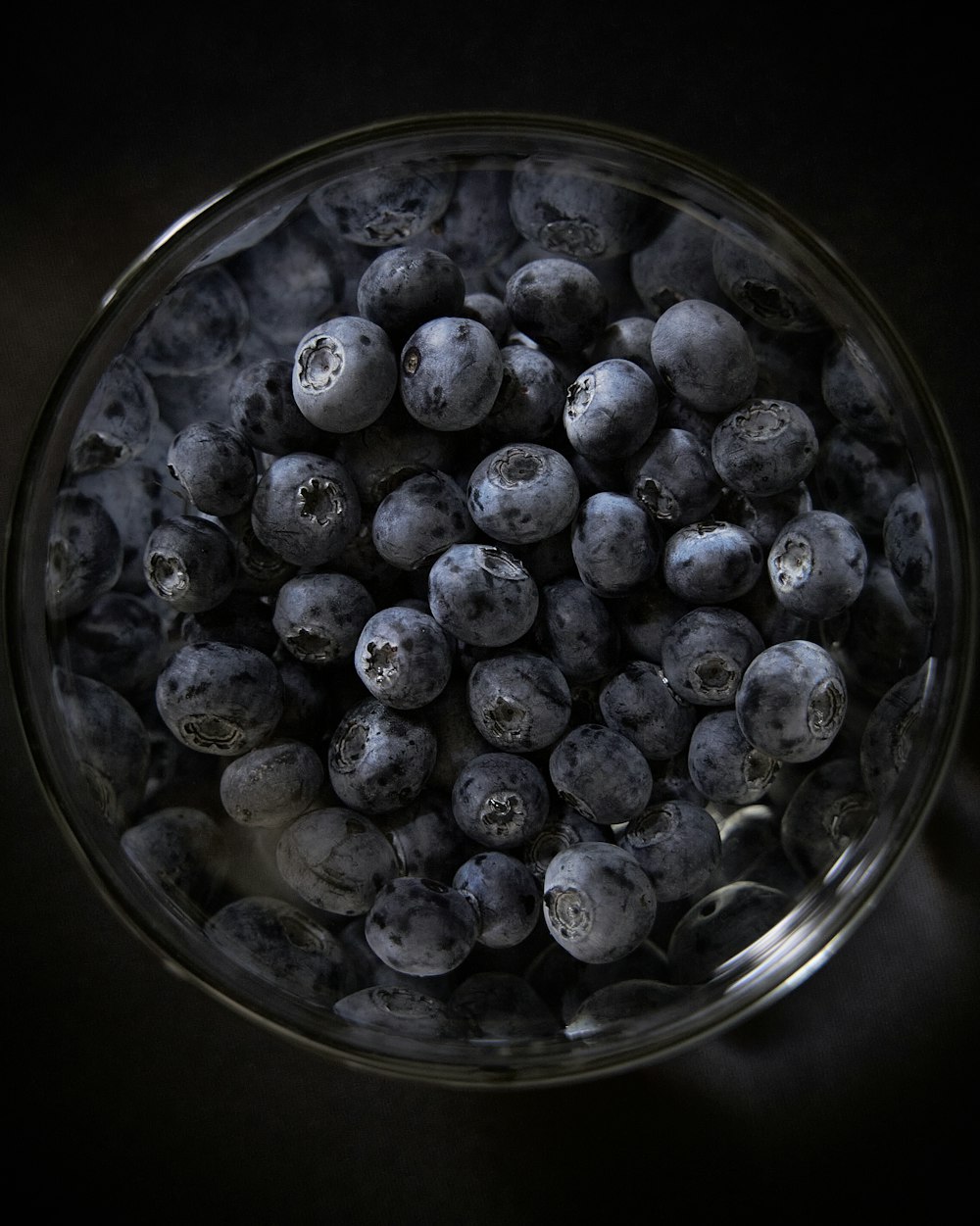 black round fruits in clear glass bowl