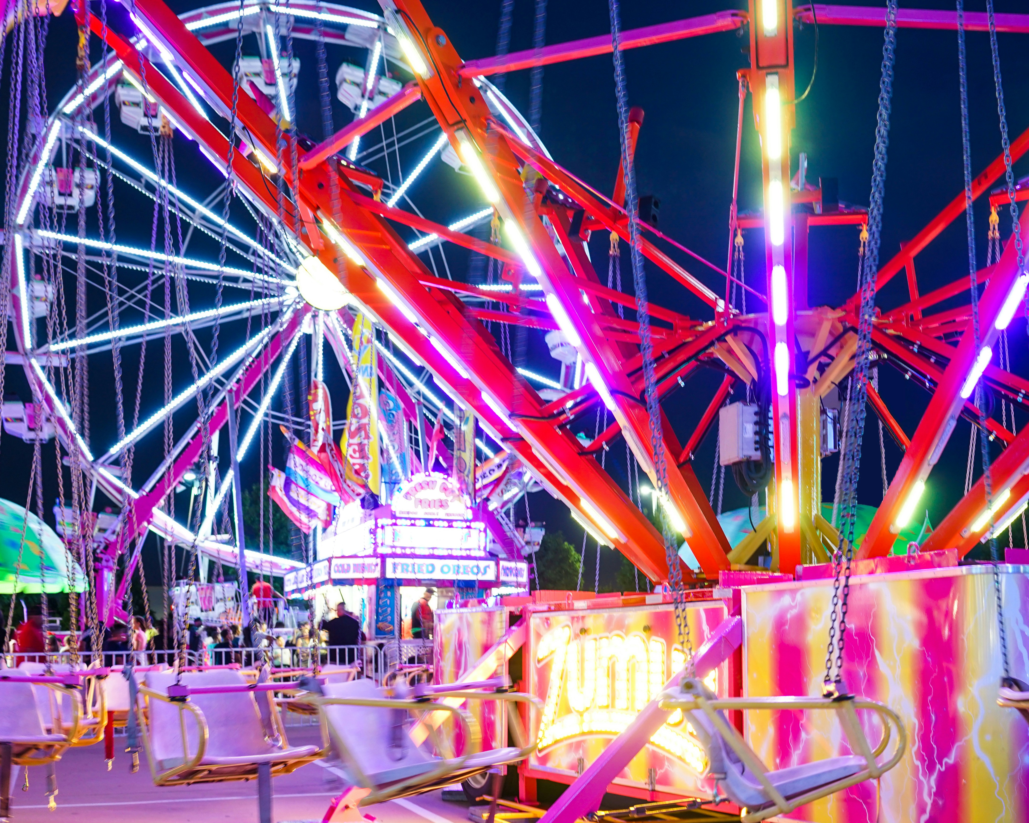 Menschen, die nachts auf einem Stuhl in der Nähe des Riesenrads sitzen