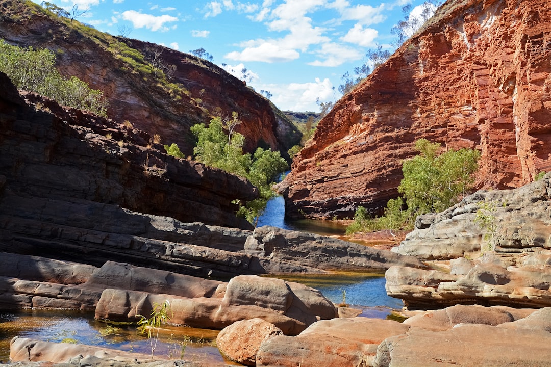 brown rocky mountain beside river under blue sky during daytime