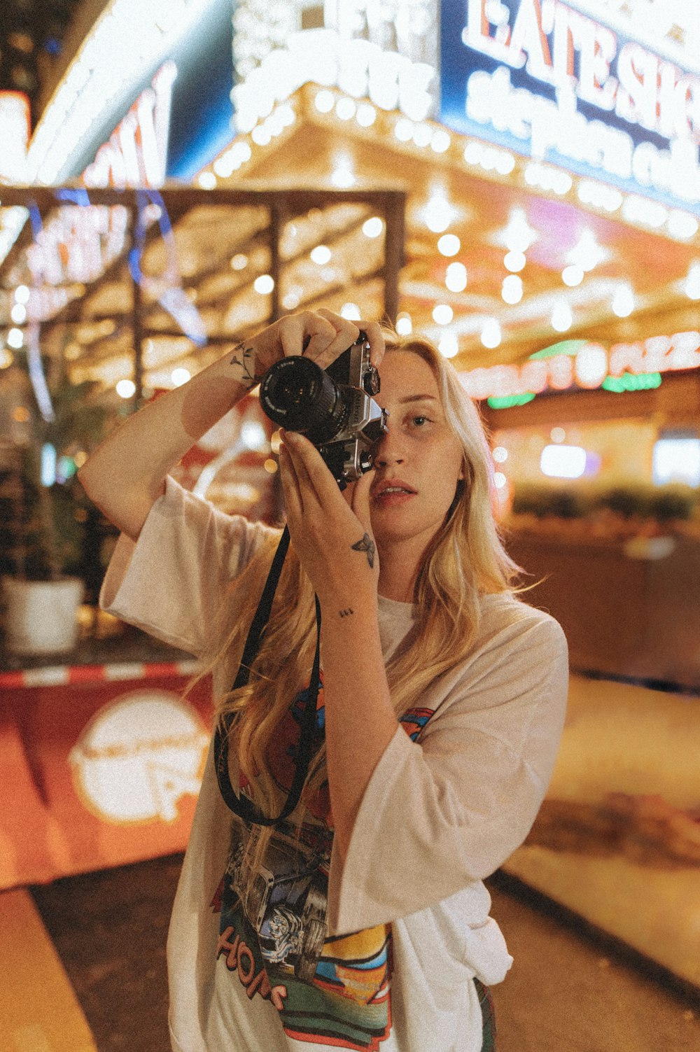 mulher na camisa branca segurando a câmera preta do dslr