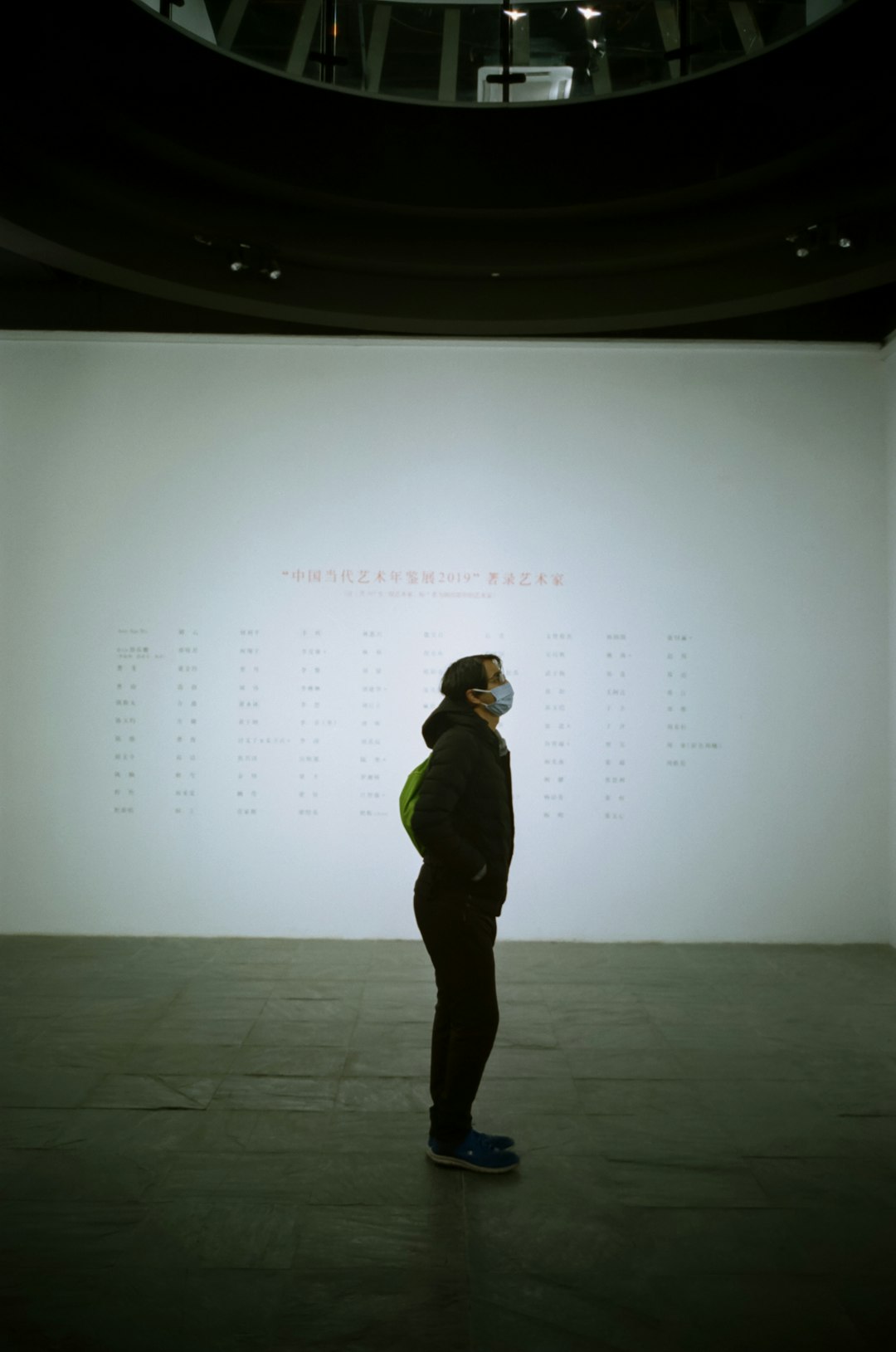 man in green hoodie standing in front of white projector screen