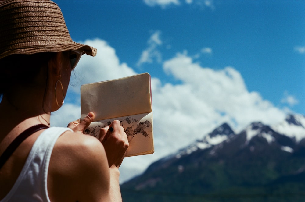 homme portant un chapeau brun tenant une carte blanche