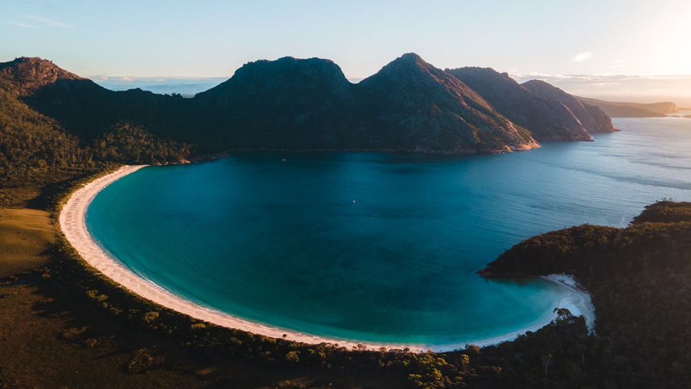 blue body of water near mountain during daytime