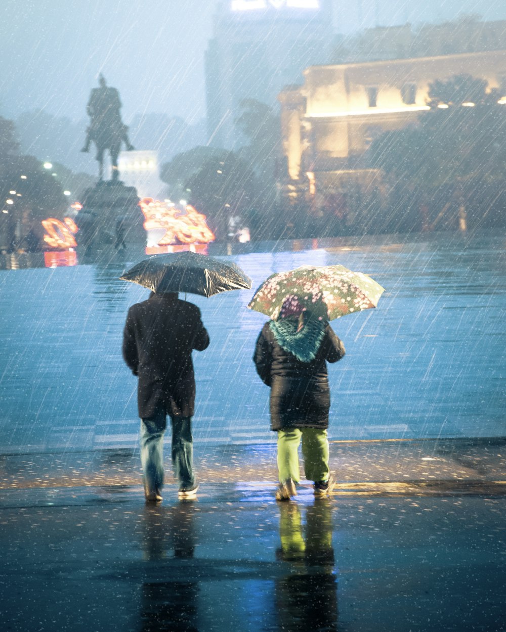 two people standing in the rain with umbrellas