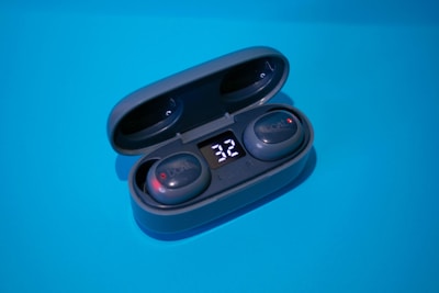 Close-up of a wireless earbud case opening to reveal earbuds with glowing LED indicators.
