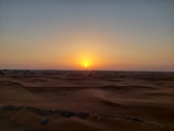 Sunset over the golden dunes of the Wahiba Sands desert in Oman.
