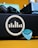 A close-up view of a music amplifier with a logo featuring vertical bars within a circle on its side. In front of it, a turquoise guitar pick is visible along with a black power cable partially connected. The background includes a teal and blue pedal unit, providing a colorful contrast to the composition.