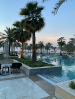 Private pool surrounded by lush greenery and sun loungers at sunset.