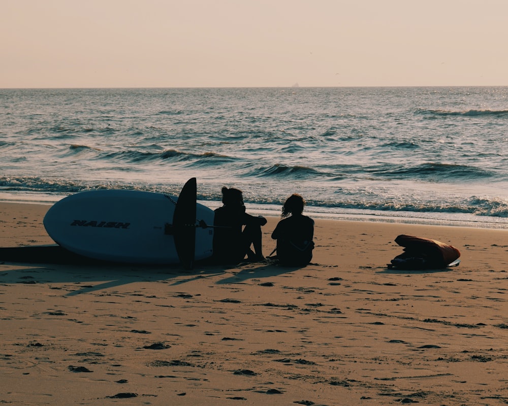 2 person sitting on beach shore during daytime