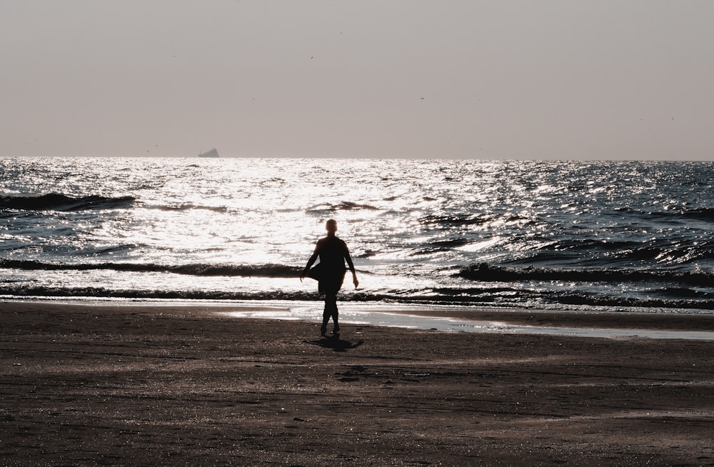 man in black jacket walking on beach during daytime