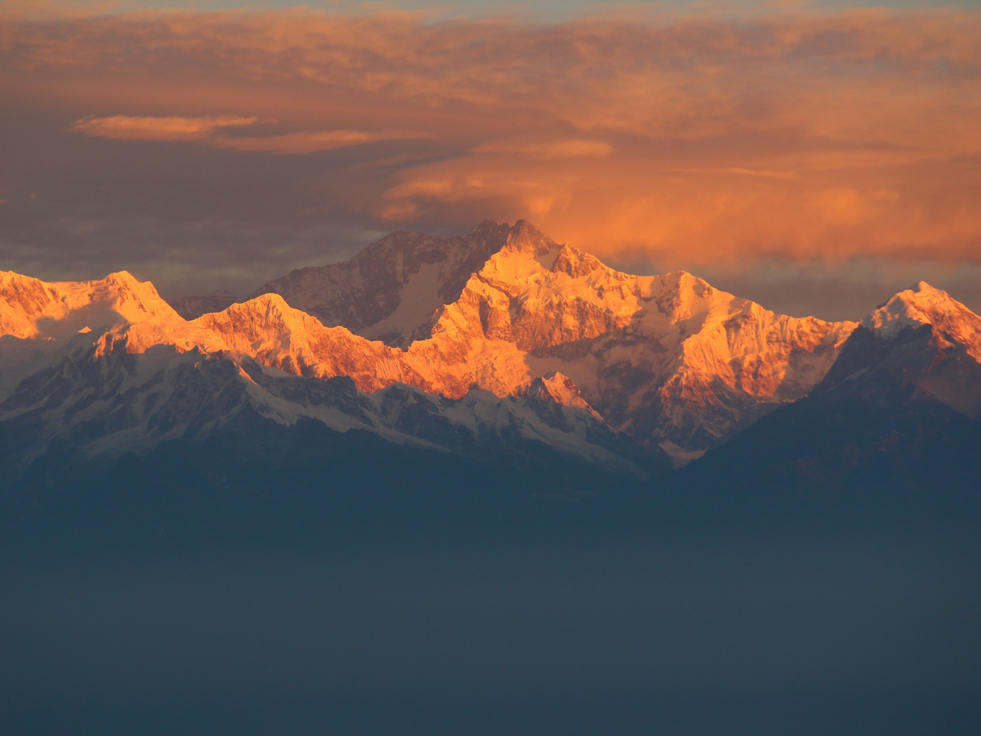 A majestic view of snow-capped Himalayan peaks from a luxury mountain lodge in Himachal, framed by rich burgundy and gold accents.