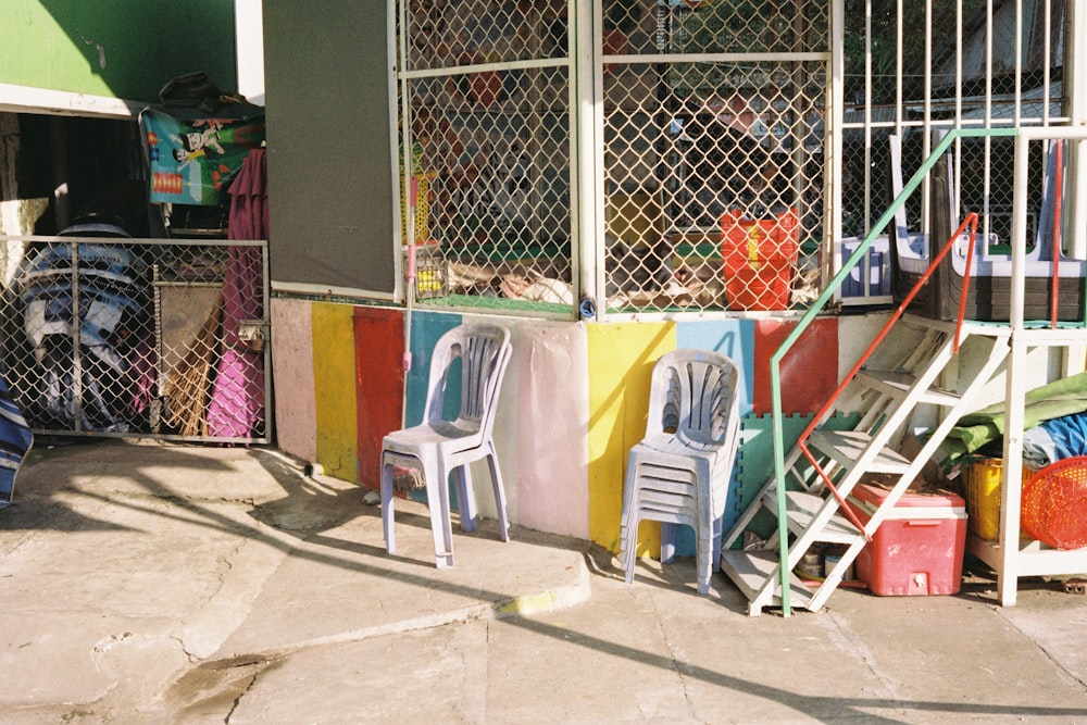 white plastic armchair beside blue metal fence