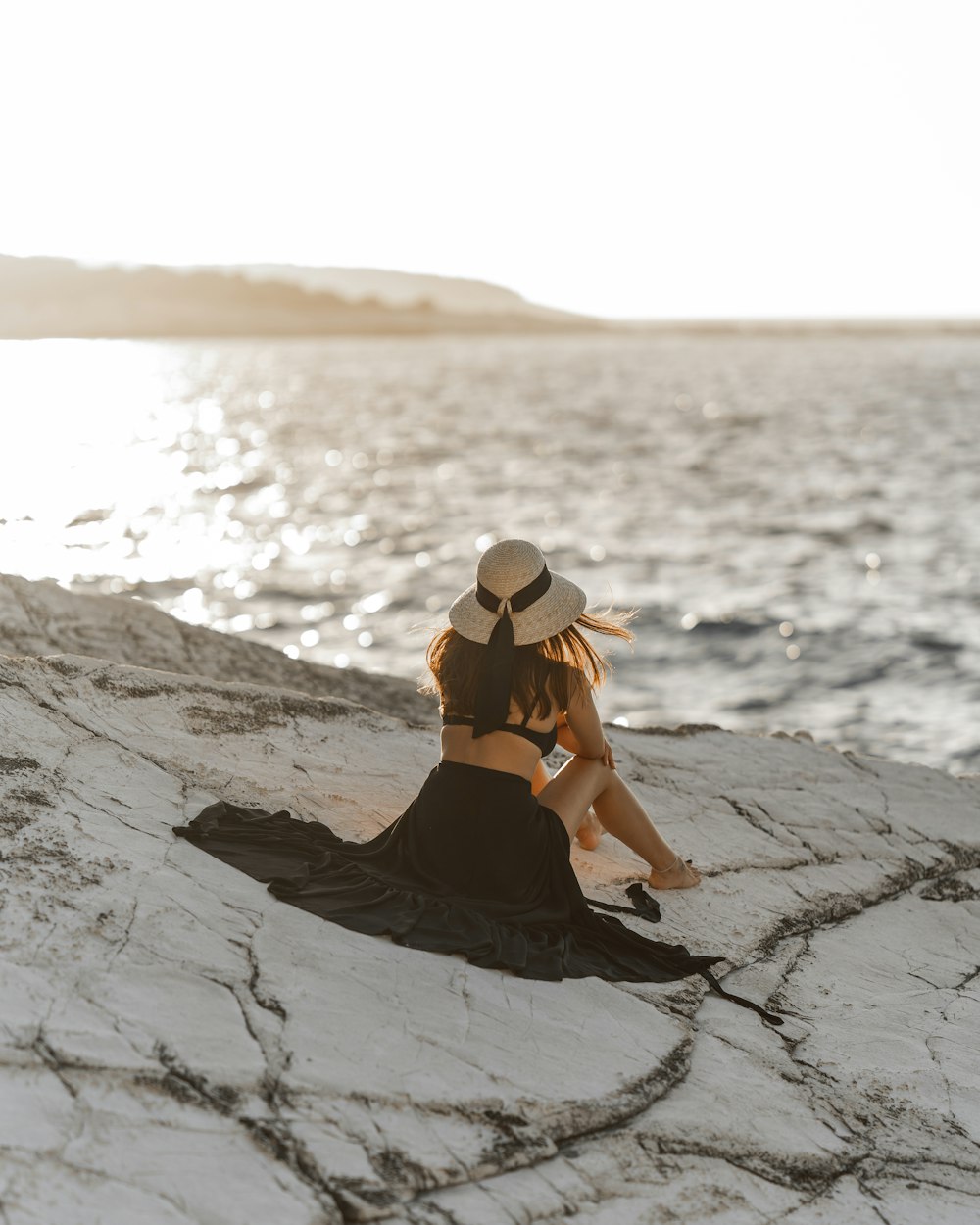 woman in black bikini sitting on rock formation during daytime