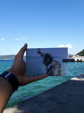 A close-up of hands gently holding an old, weathered photograph of historic Houston landmarks.