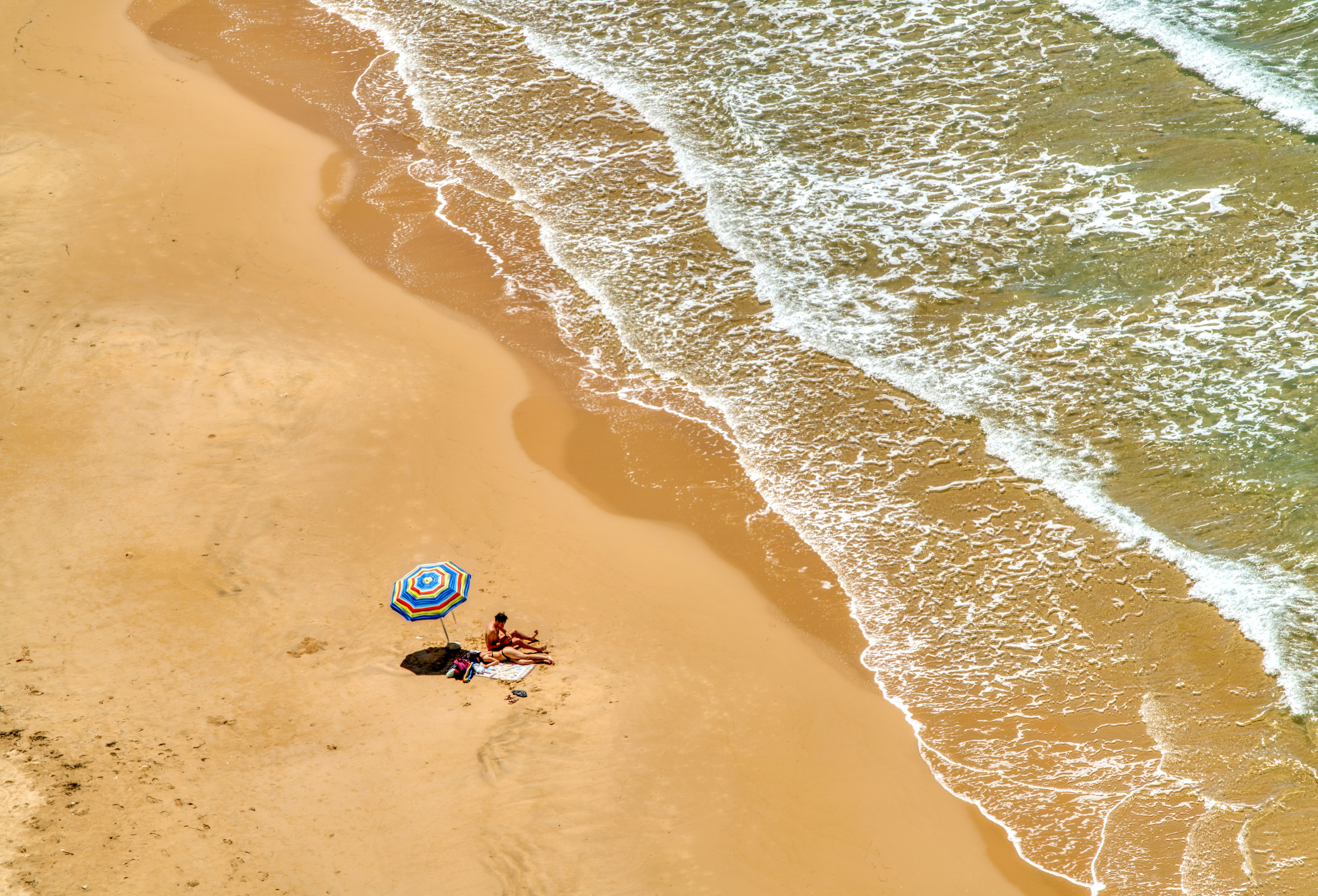 person in blue and white wetsuit riding blue and white surfboard on beach during daytime