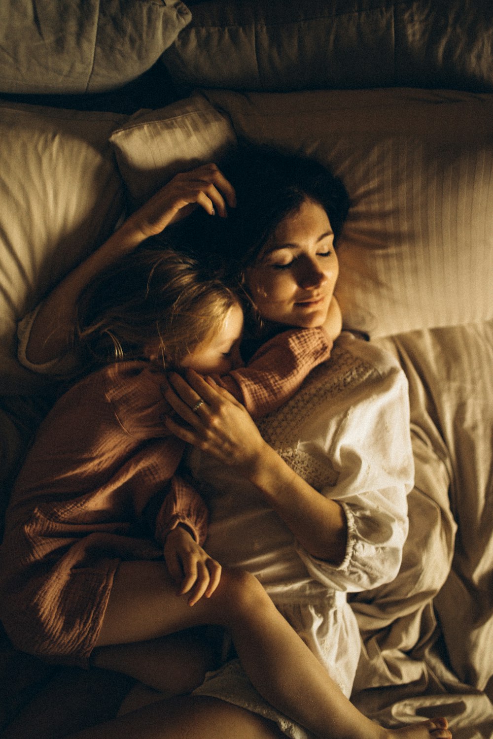 woman hugging girl on bed