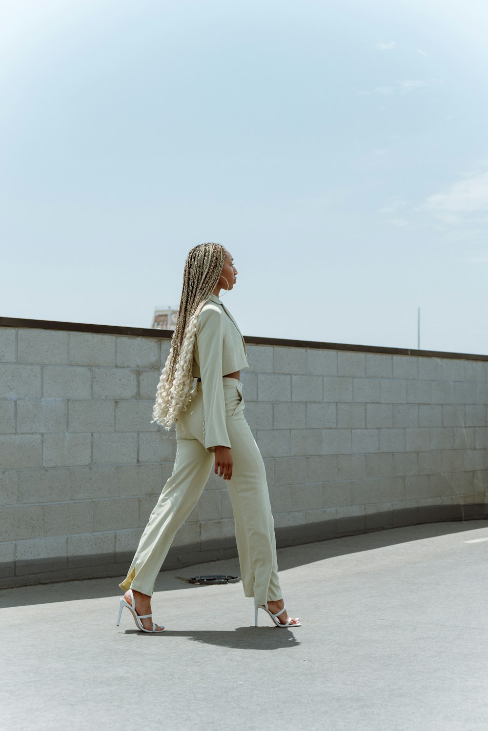 woman in white pants and white cardigan standing on gray concrete floor during daytime