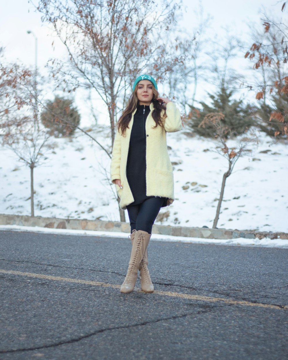 woman in beige coat standing on road during daytime