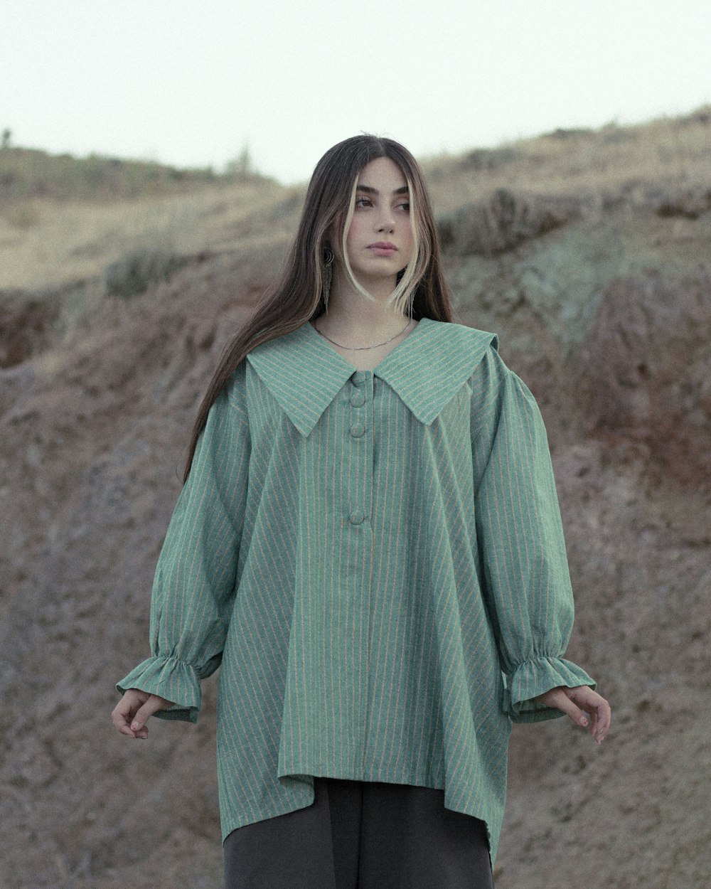 woman in green long sleeve dress standing on brown field during daytime