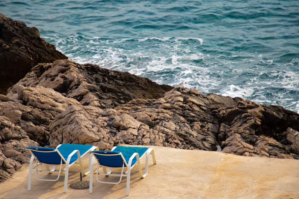 blue and white folding chair on brown sand near body of water during daytime