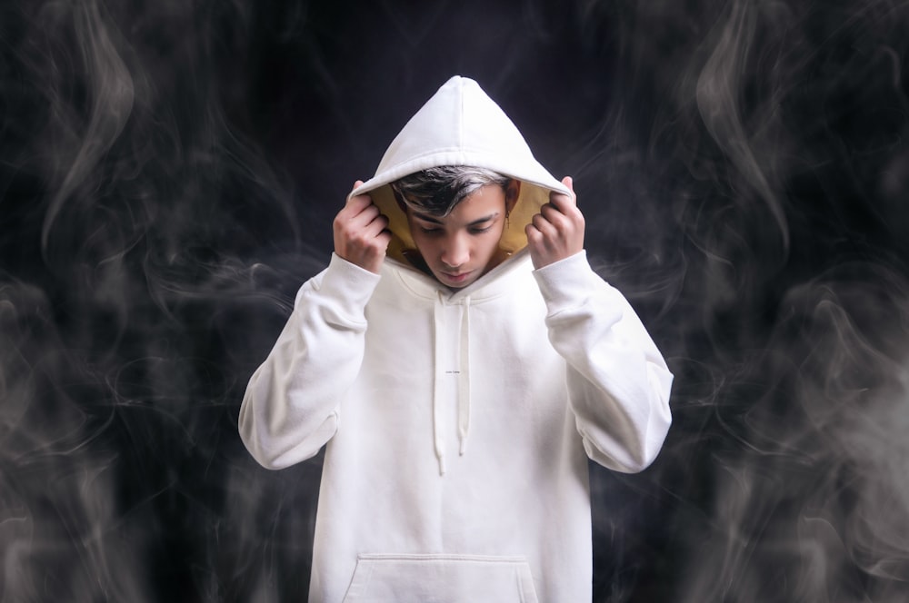 man in white hoodie covering his face with his hands