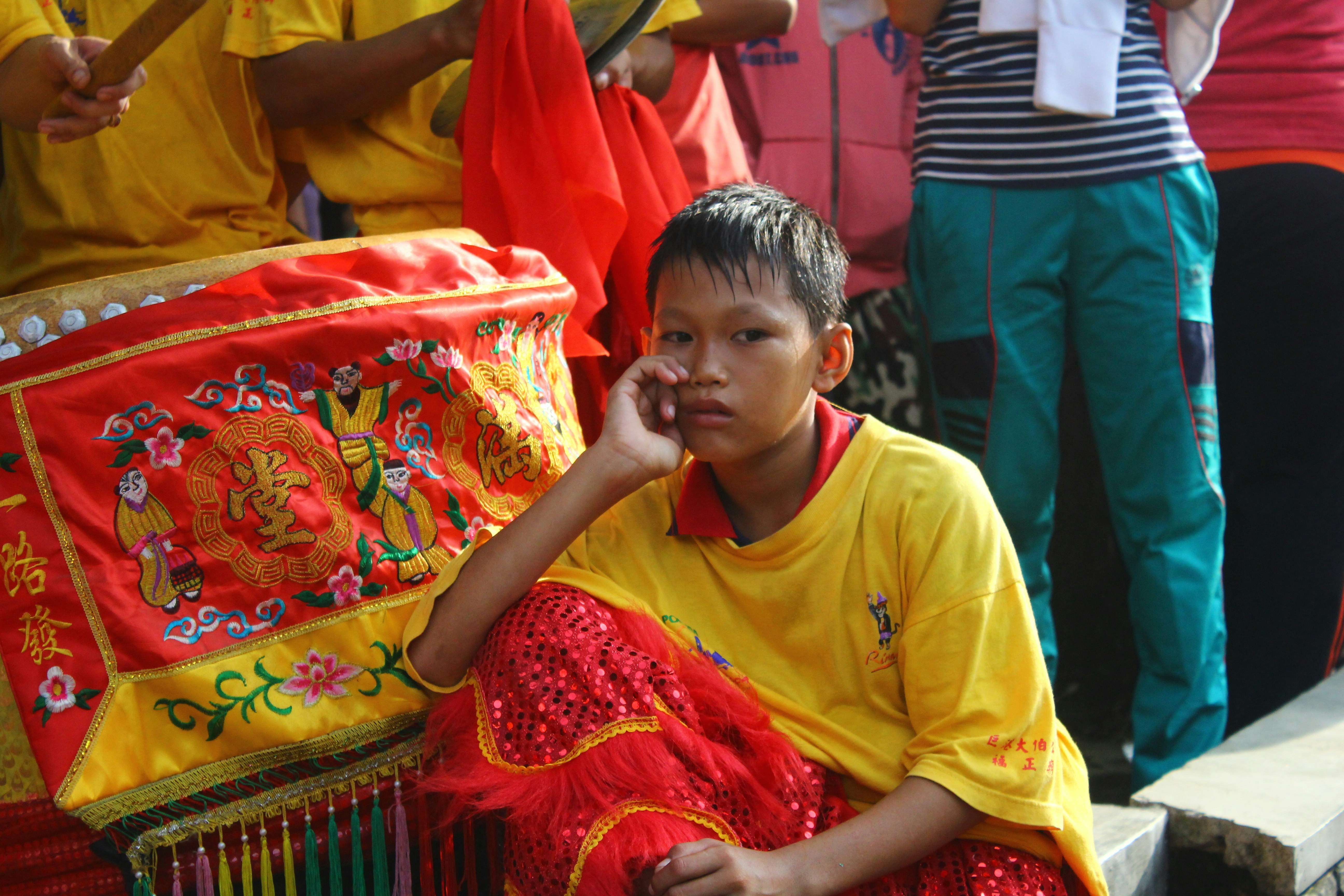 Wanita dengan kaos leher kru kuning duduk di atas tekstil merah dan putih