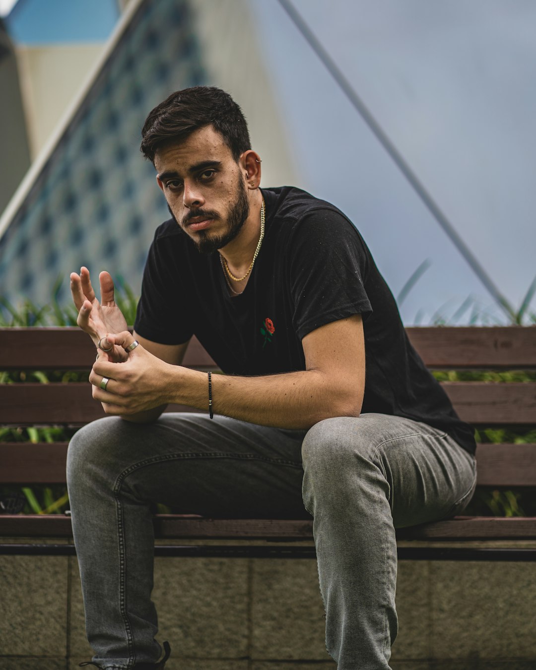 man in black crew neck t-shirt and gray denim jeans sitting on brown wooden bench