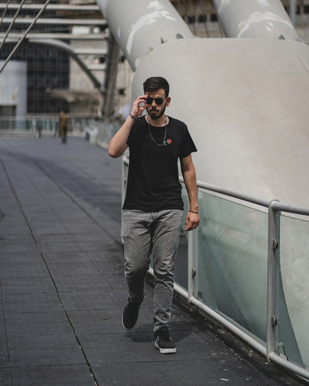 man in black crew neck t-shirt and gray denim jeans wearing black sunglasses