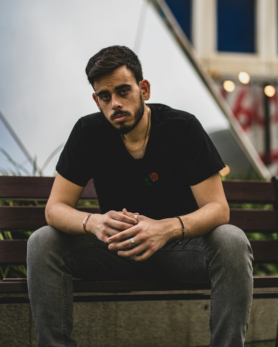 man in black crew neck t-shirt and blue denim jeans sitting on brown wooden bench