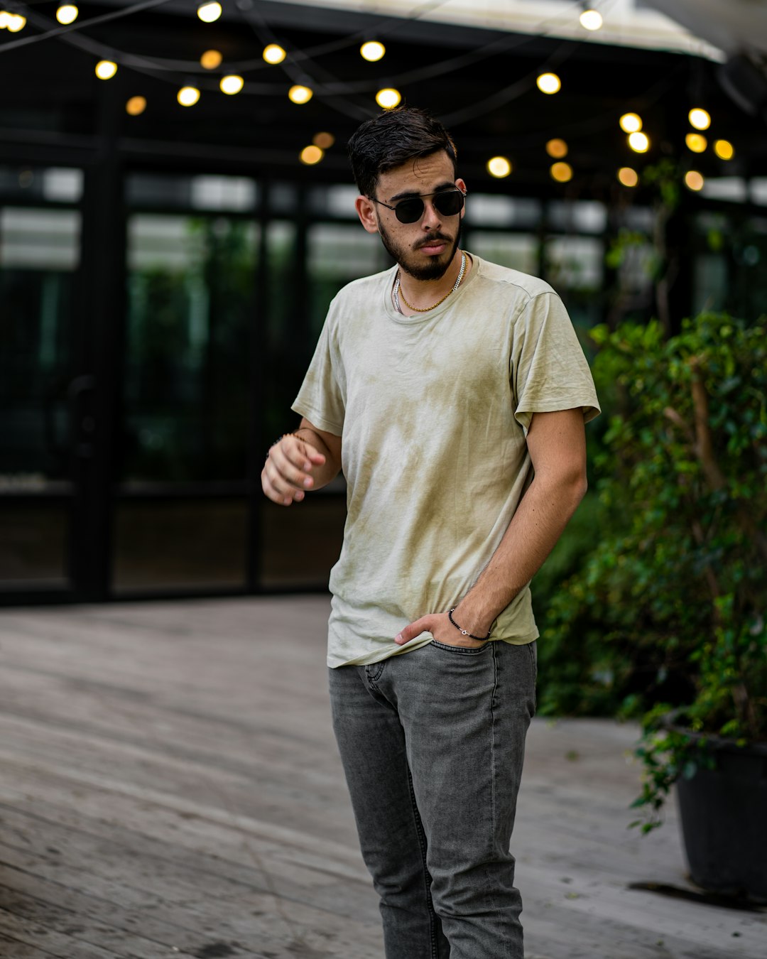 man in white crew neck t-shirt and blue denim jeans standing on sidewalk during daytime