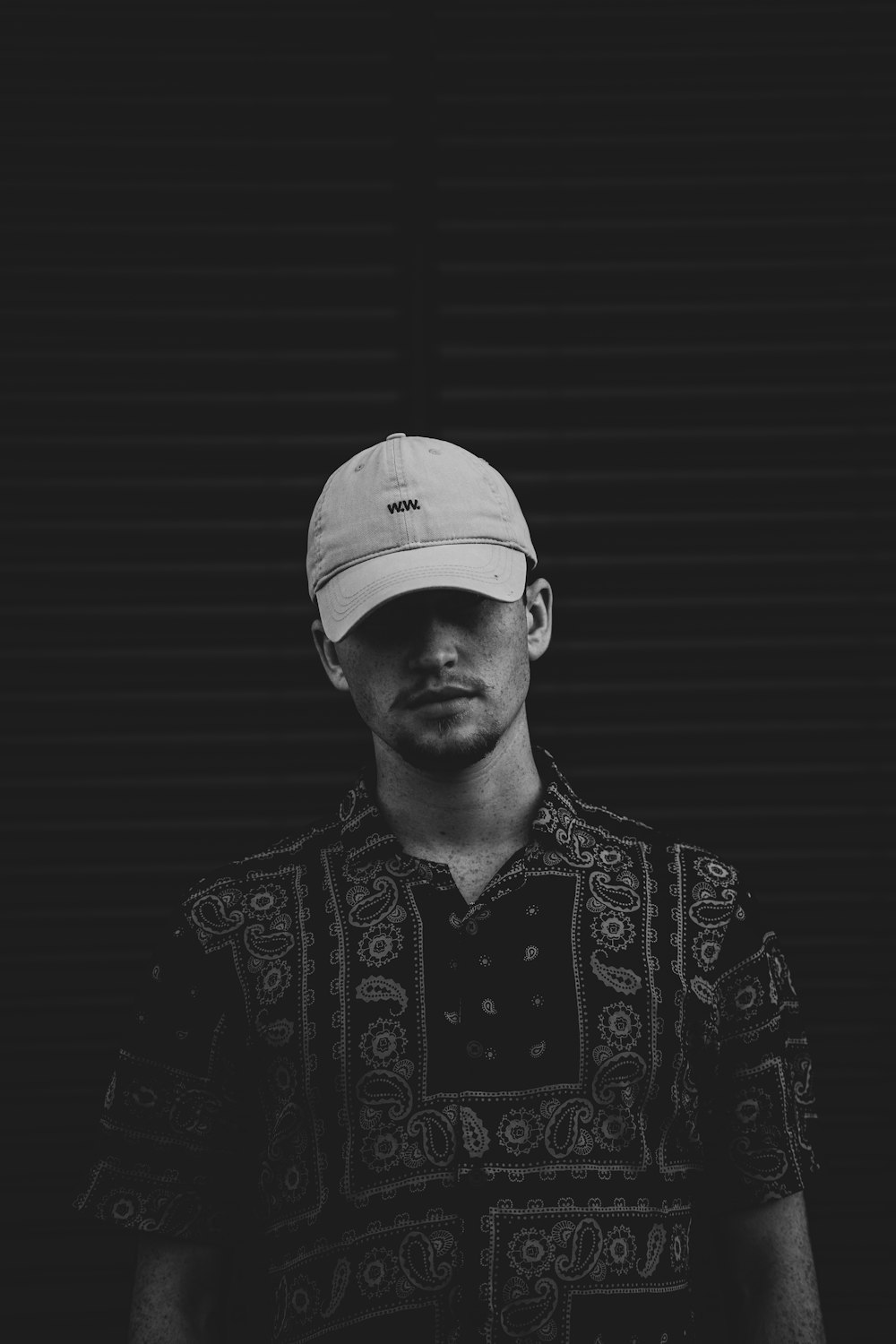 man in black and white floral button up shirt wearing white cap