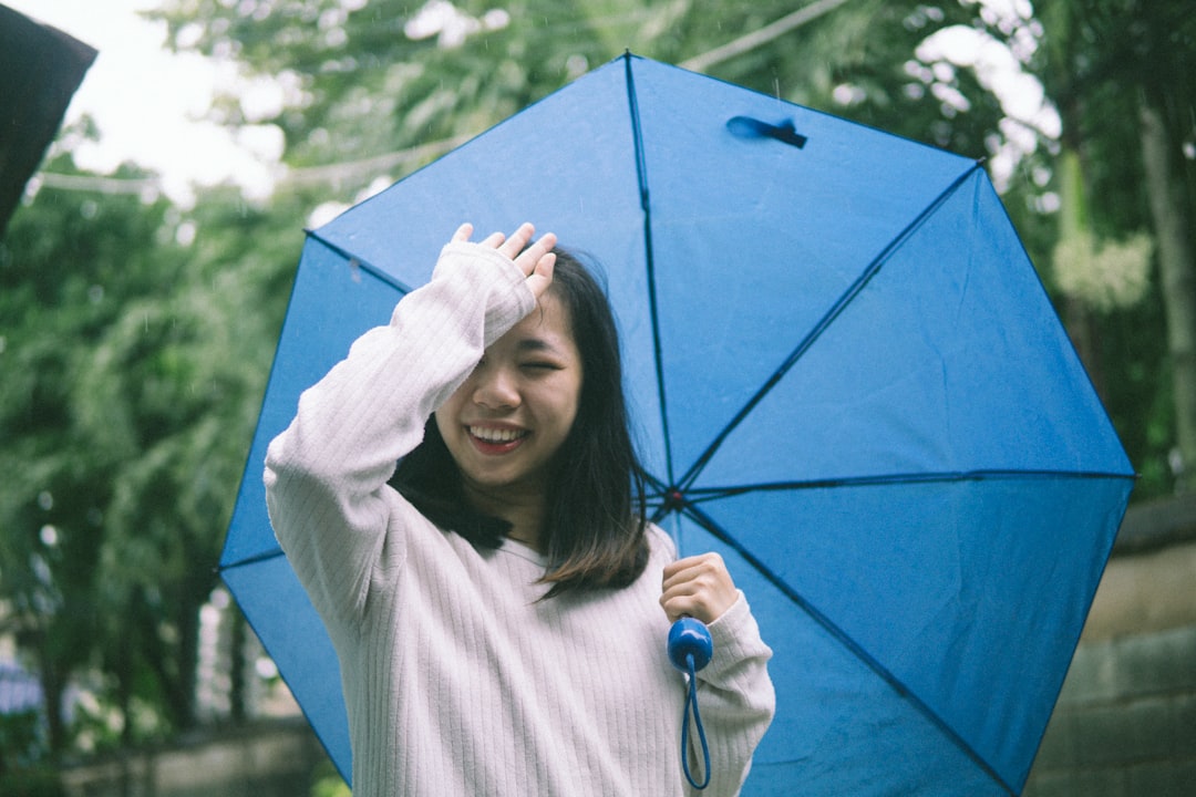 woman in white long sleeve shirt holding blue umbrella