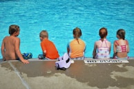 woman in pink shirt sitting beside girl in pink shirt on beach during daytime