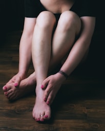 woman in black shorts sitting on brown wooden floor