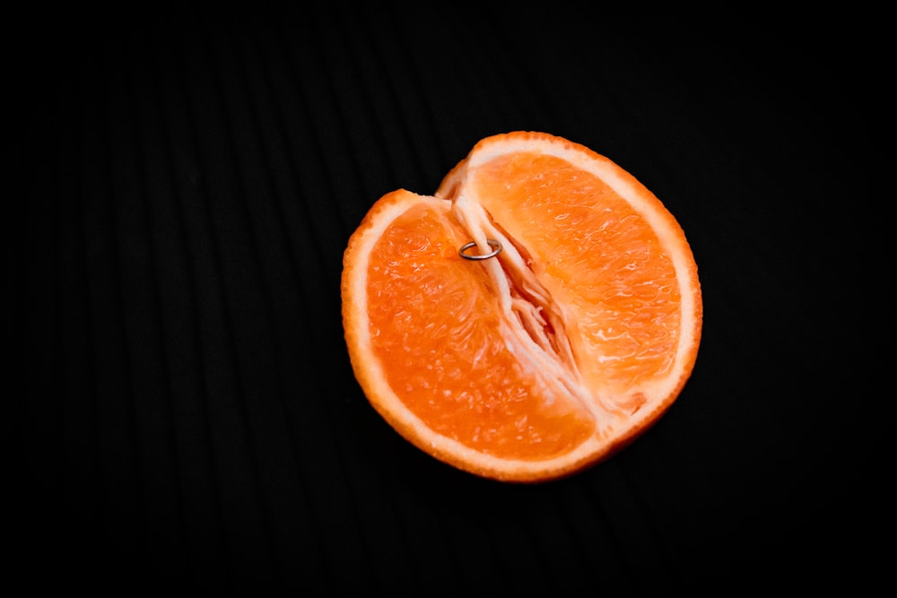 in Scheiben geschnittene Orangenfrüchte auf schwarzer Oberfläche