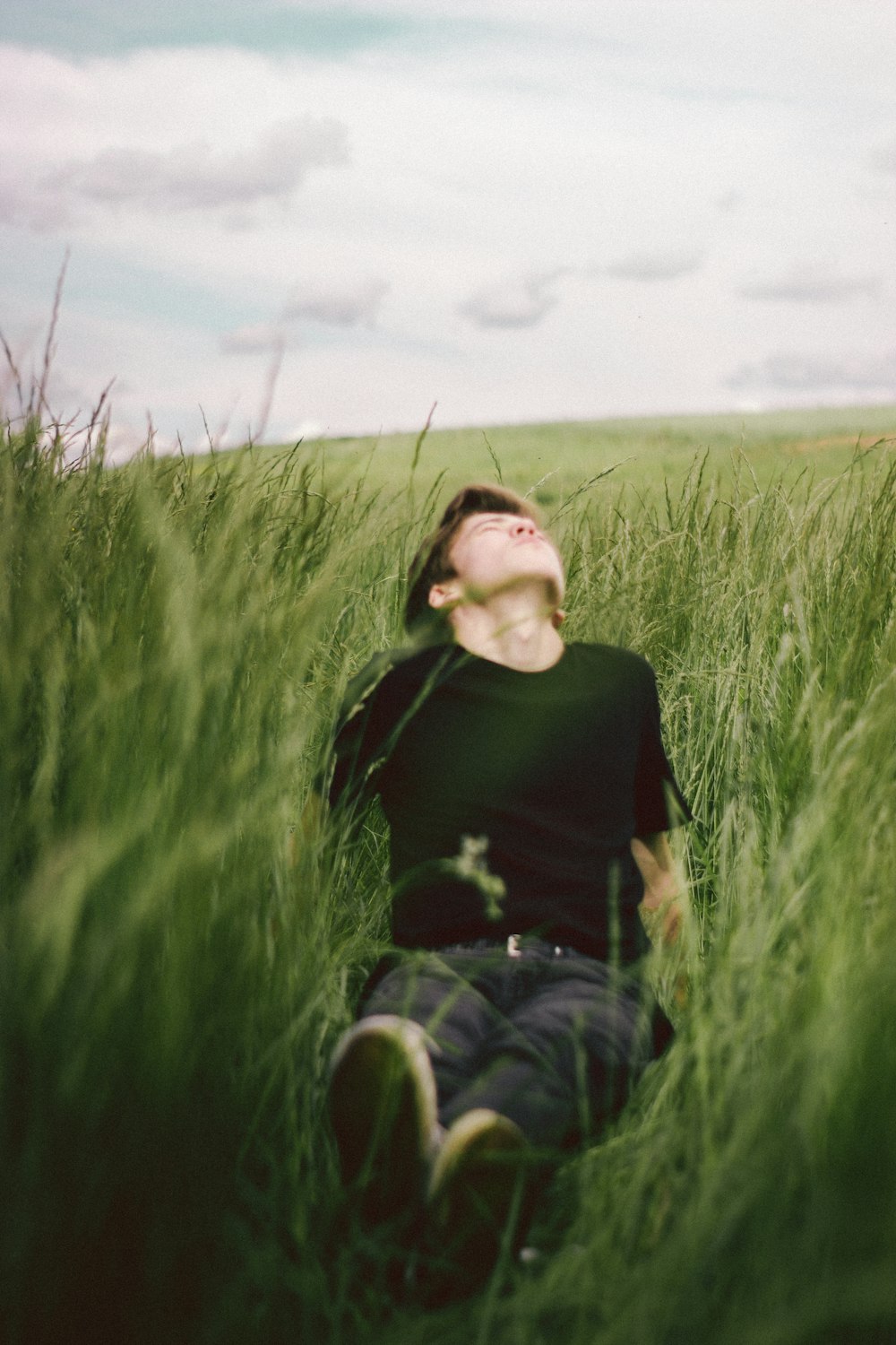 woman in black long sleeve shirt and blue denim jeans sitting on green grass field during