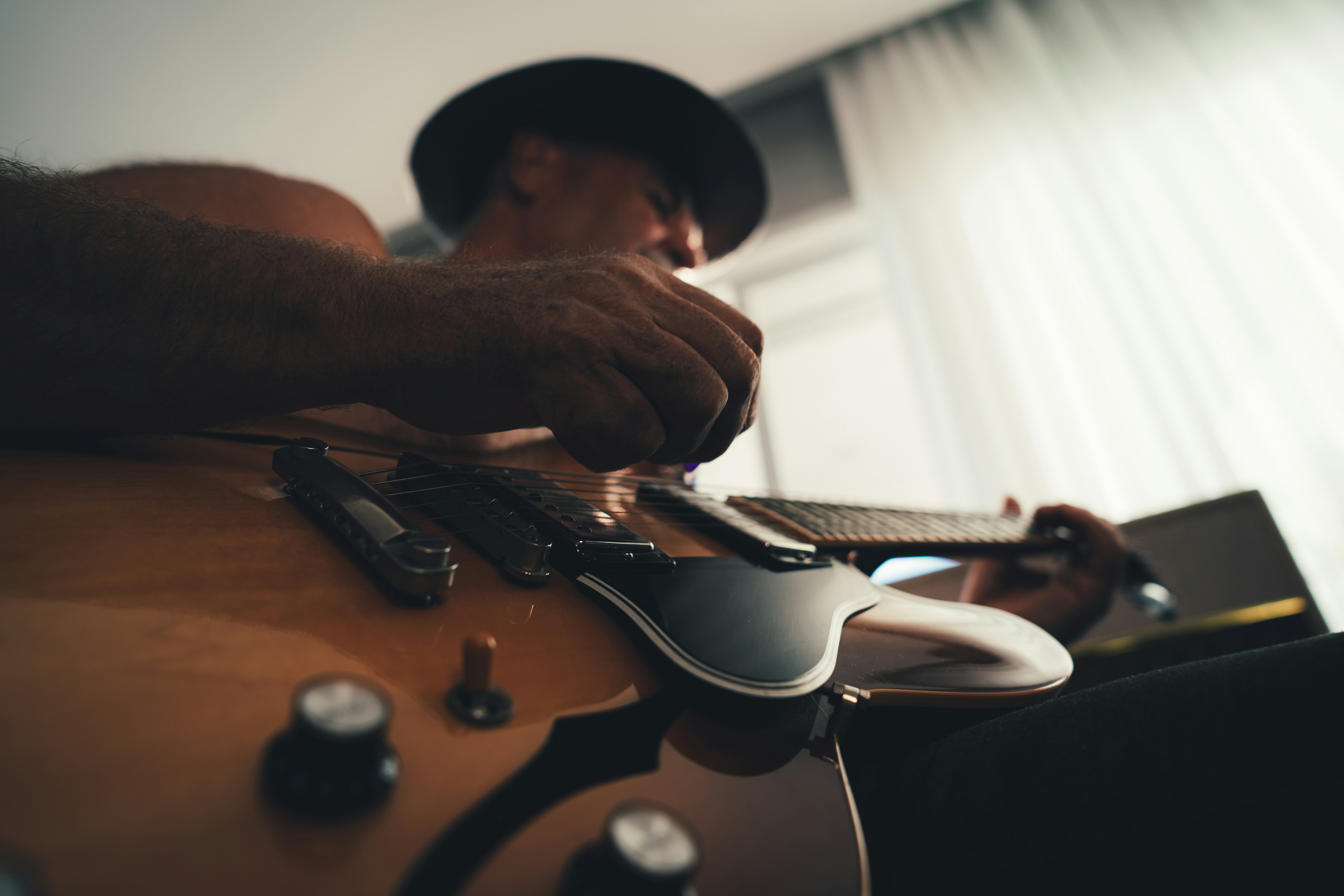 man playing guitar in front of window