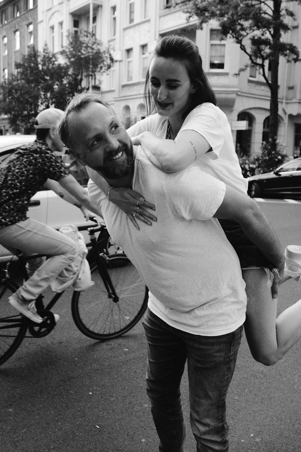 man in white shirt and black denim jeans holding girl in black and white photography