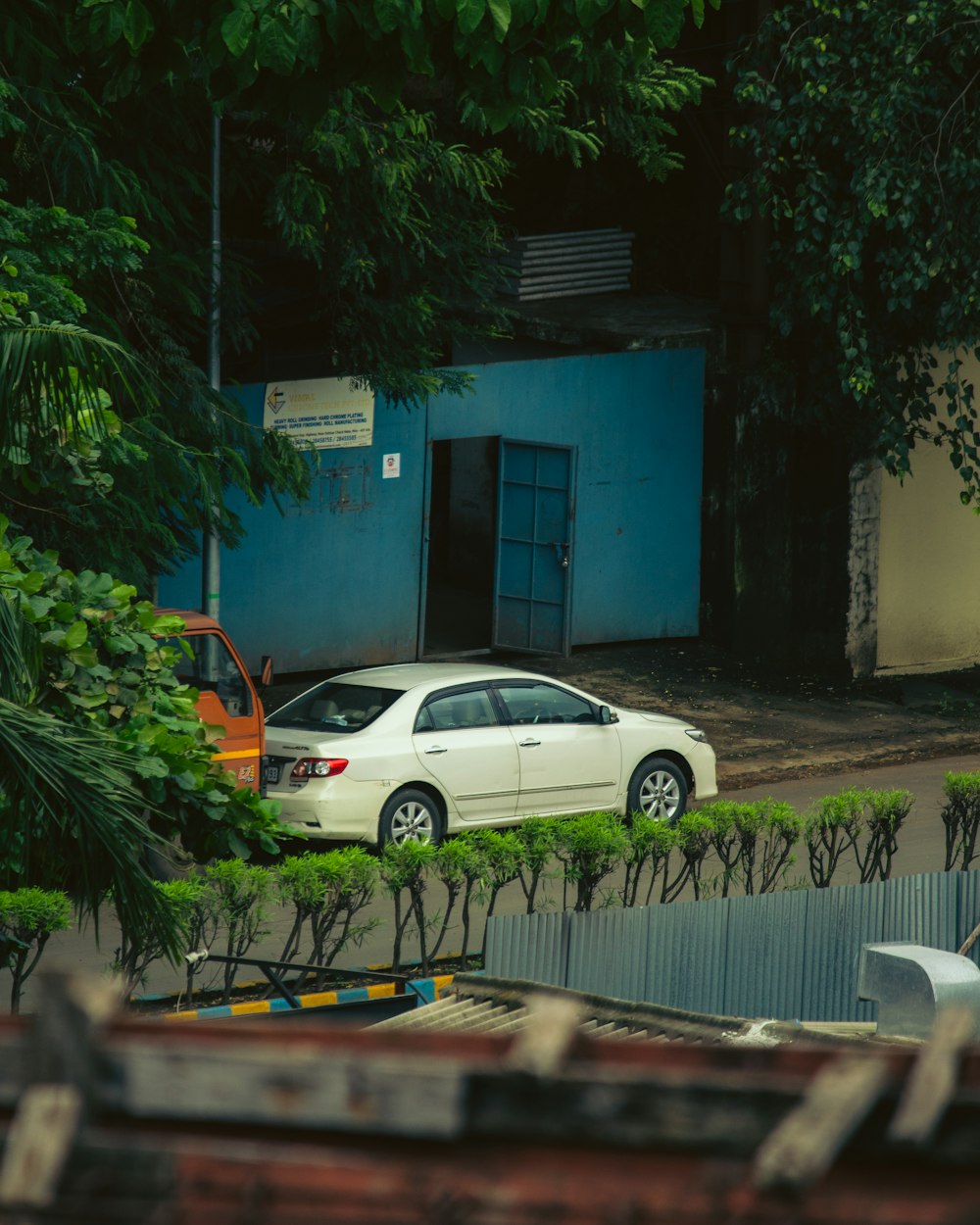 white sedan parked beside blue and white concrete building during daytime