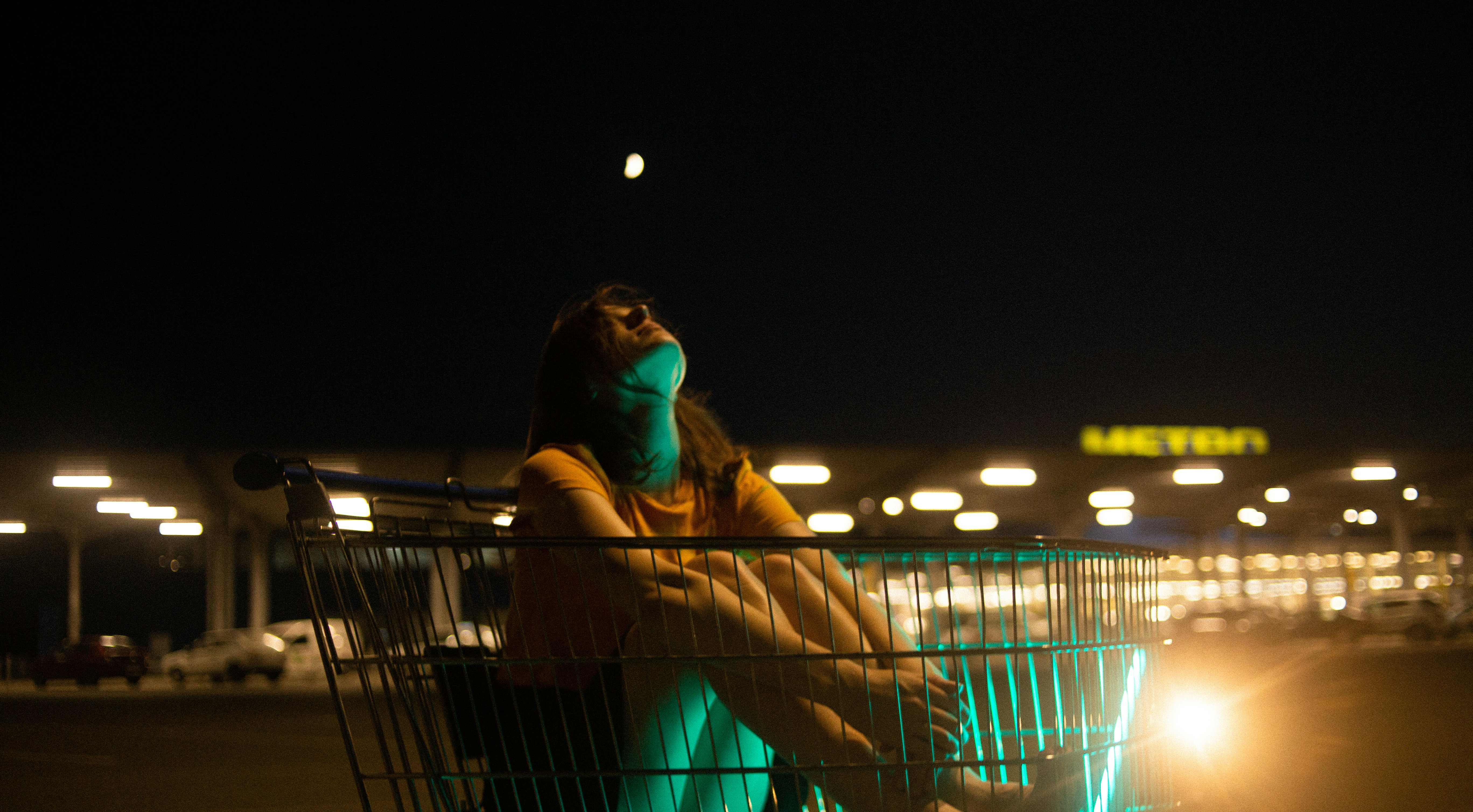 woman in blue and yellow dress sitting on gray shopping cart