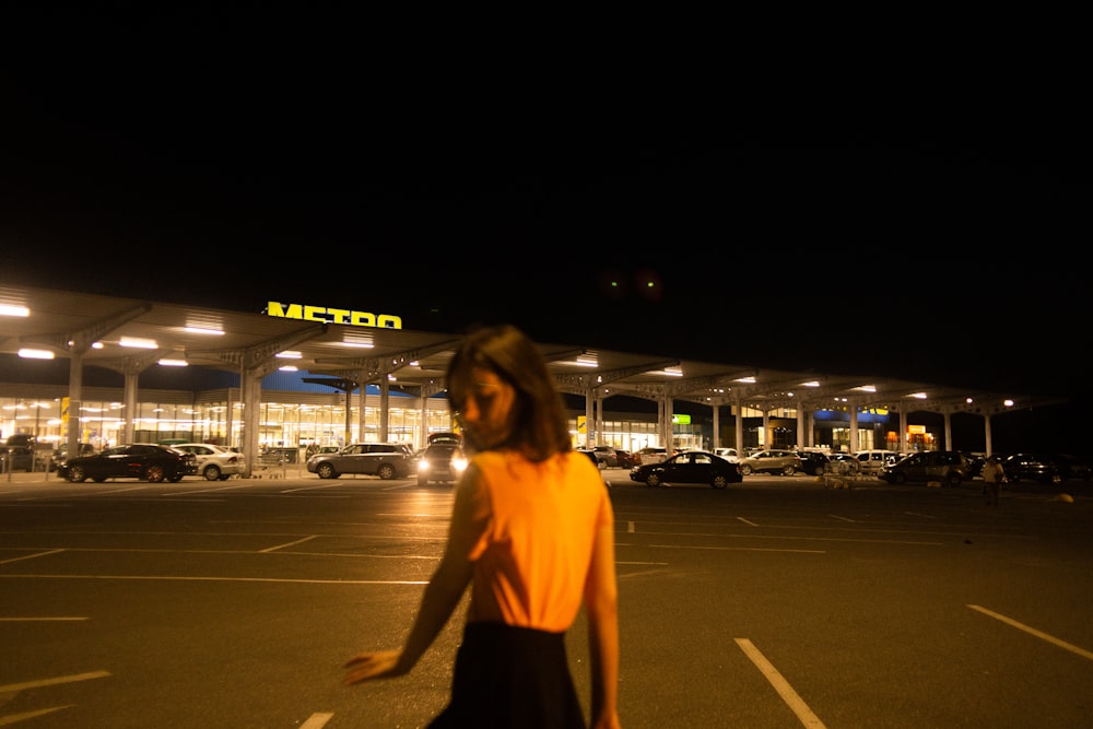 woman in yellow shirt standing on sidewalk during night time