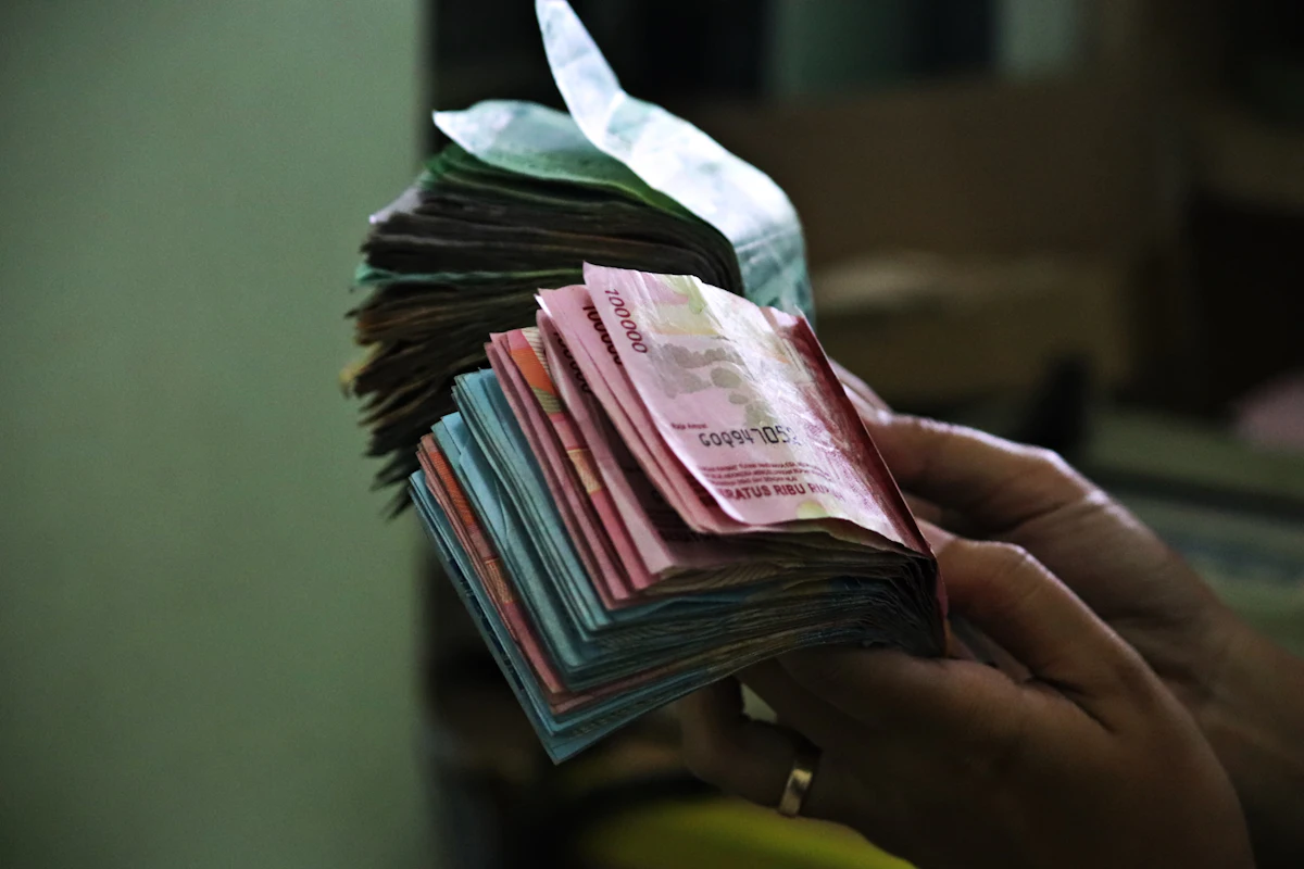 Tangan memegang setumpuk uang rupiah