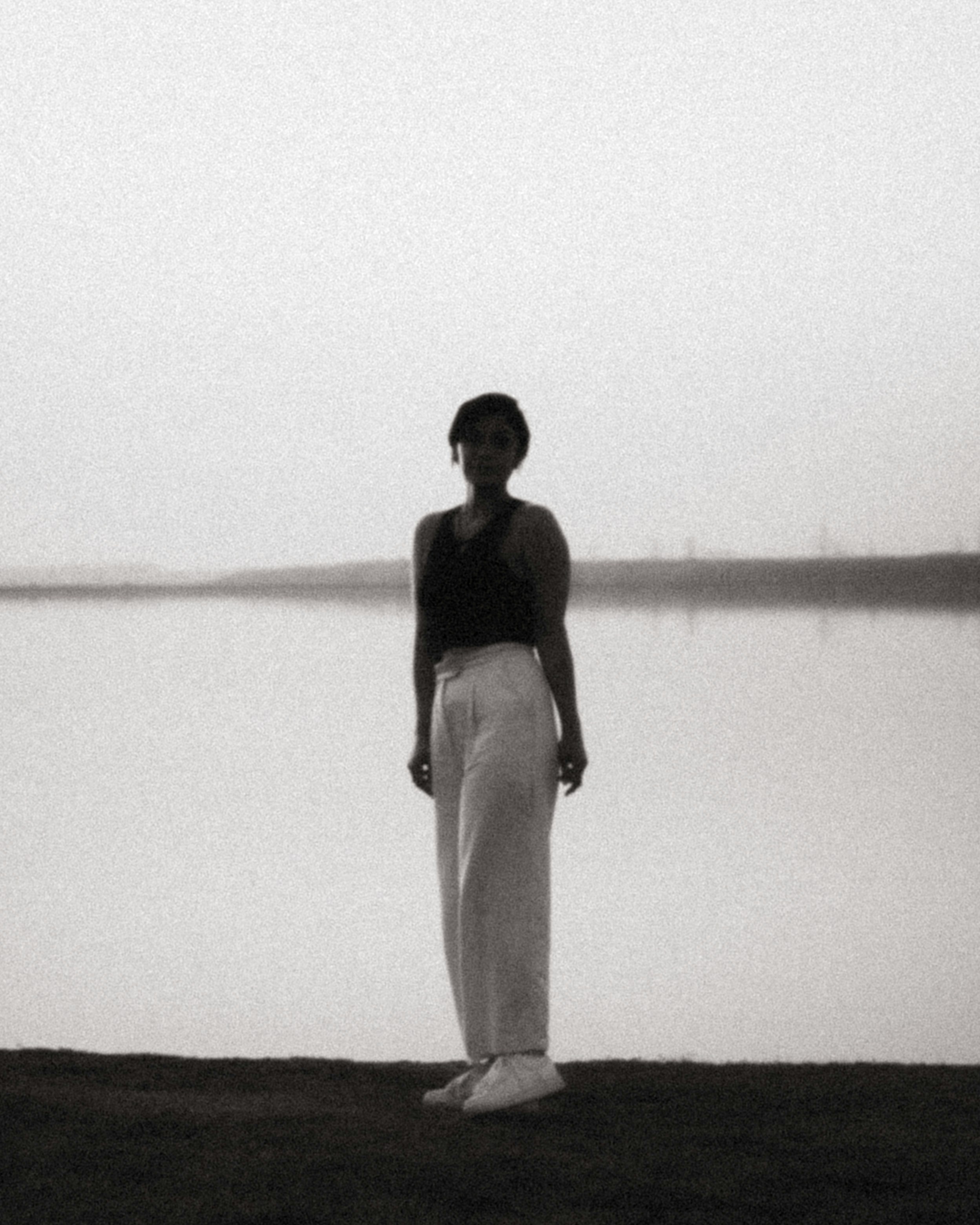 woman in black tank top and white pants standing on shore