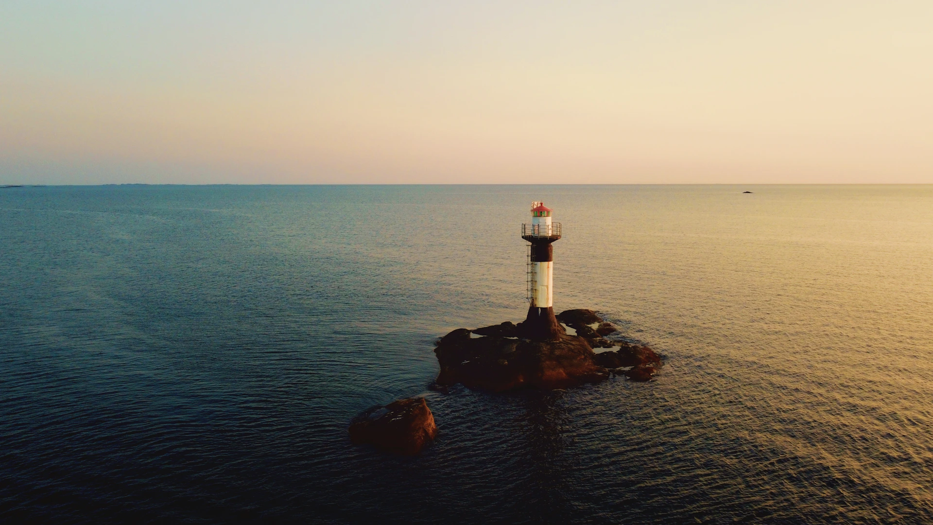 white and red lighthouse on rock formation near body of water during daytime