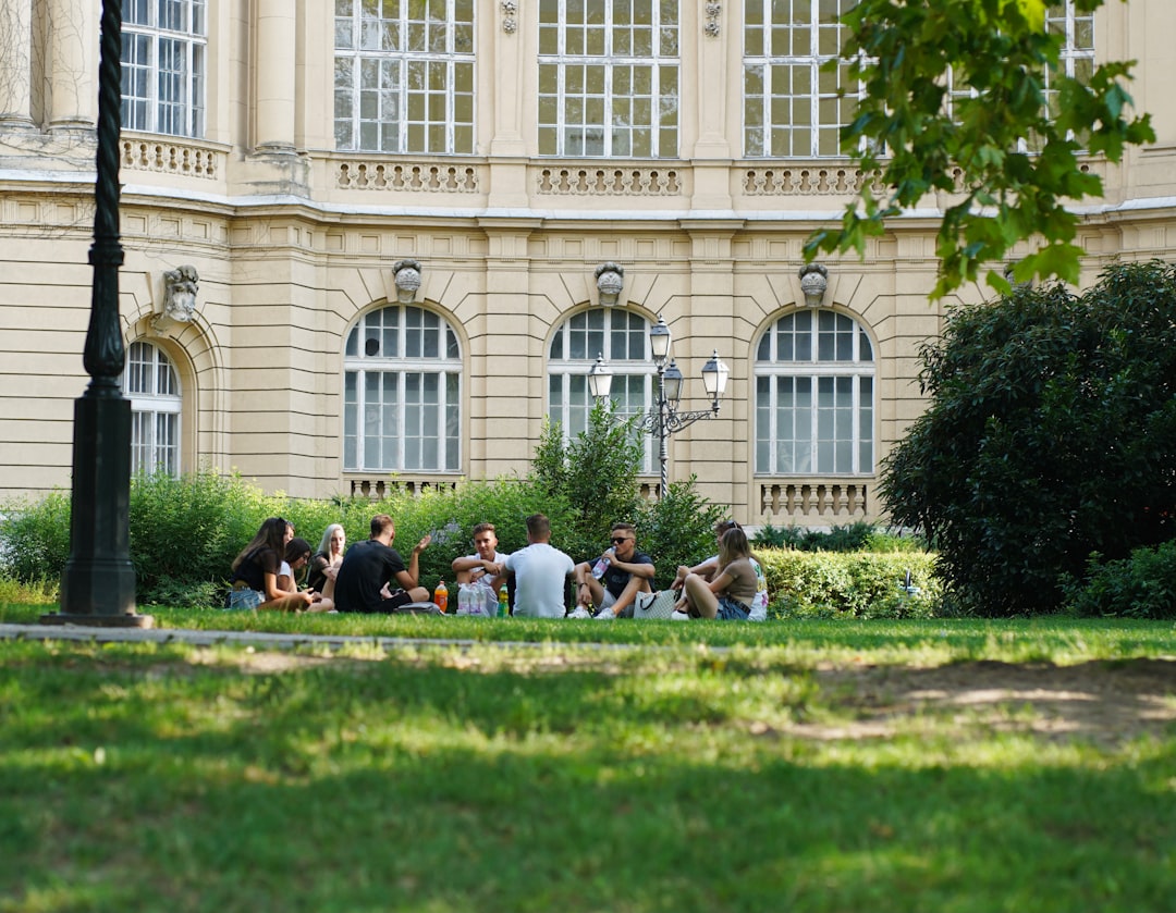 people sitting on green grass field near white concrete building during daytime