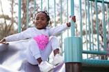 A little girl and boy playing together on a playground slide, their faces lit with pure joy.